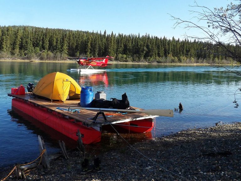 Das Floß liegt ruhig am Ufer, während ein Wasserflugzeug auf dem See landet – Alltag auf dem Yukon, irgendwo nördlich von Whitehorse.